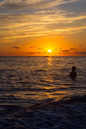 Summer sea sunset on the pebble beach, the sun, waves and clouds, beautiful dramatic lightingの写真素材