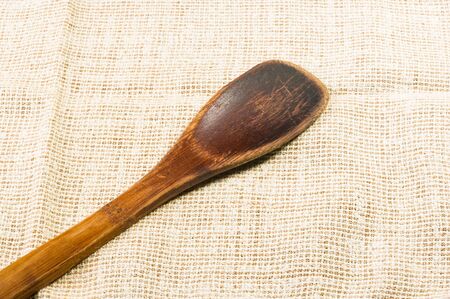 light rustic coarse canvas fabric and a worn wooden spoon, close-up, backgroundの写真素材