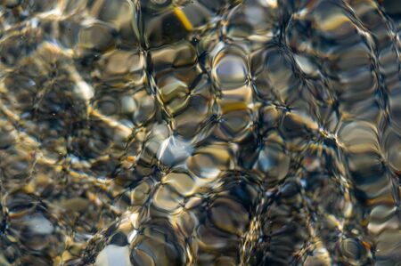 pebble stones on the sea beach on a warm summer day, the rolling waves of the blue sea with white foamの写真素材