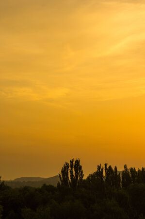 Landscape with dramatic light - beautiful golden sunset with saturated sky and clouds, peaceful nature serene background.の写真素材