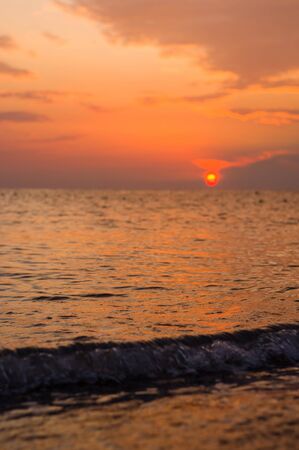 Summer sea sunset on the pebble beach, the sun, waves and clouds, beautiful dramatic lightingの写真素材