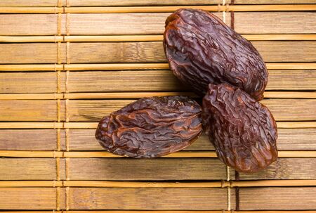 Big luxury dried date fruit on the bamboo mat, kurma ramadan kareem concept.