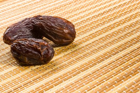 Big luxury dried date fruit on the bamboo mat, kurma ramadan kareem concept.