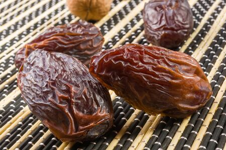 Big luxury dried date fruit on the bamboo mat, kurma ramadan kareem concept.