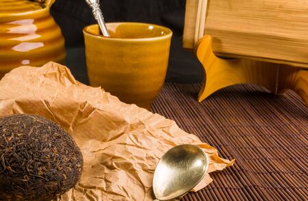 Chinese pressed PU-erh tea on wrapping paper and tea accessories, close-upの写真素材