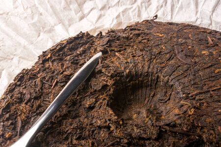 Chinese pressed PU-erh tea on wrapping paper and tea knife, close-upの写真素材