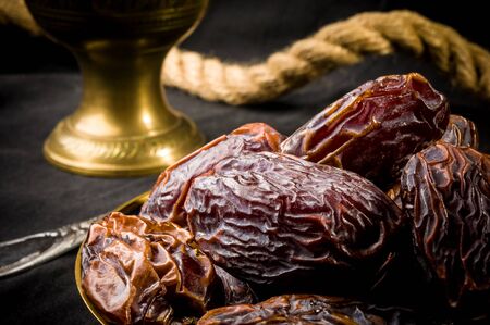 Big luxury dried date fruit in bowls on the dark surface, kurma ramadan kareem concept.の写真素材