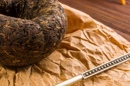 Chinese pressed PU-erh tea on wrapping paper and tea accessories on a bamboo Mat, close-upの写真素材
