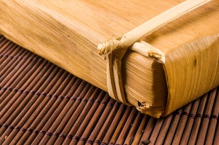 Chinese pressed PU-erh tea in bamboo leaf packaging on a bamboo Mat, close-upの写真素材
