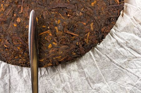 Chinese pressed PU-erh tea on wrapping paper and tea knife, close-upの写真素材