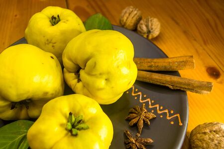 still life - large yellow quince fruits on a ceramic plate, with anise, cinnamon, and walnutsの写真素材