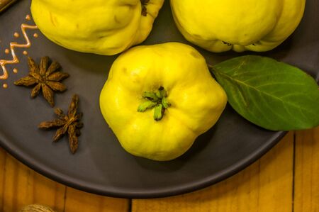 still life - large yellow quince fruits on a ceramic plate, with anise, cinnamon, and walnutsの写真素材