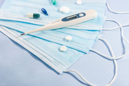 Background concept for news about the novel coronavirus COVID-19 pandemic, antiviral medical mask for protection against coronavirus. Surgical protective mask. Medical respiratory bandage face and thermometer, lettering on copy space.の写真素材
