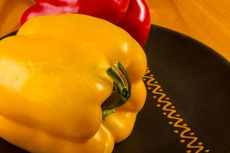 a colorful mix of the freshest red and yellow paprika, bell pepper in ceramic plate on wooden background, close upの写真素材