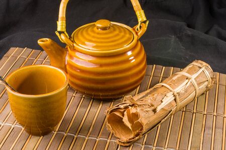 Chinese pressed PU-erh tea in bamboo leaf packaging and tea accessories on a bamboo Mat, close-upの写真素材