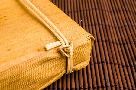 Chinese pressed PU-erh tea in bamboo leaf packaging on a bamboo Mat, close-upの写真素材