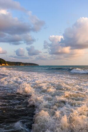 sea landscape is a pebbly beach with waves in white foam, a beautiful sky with clouds, a warm summer dayの写真素材