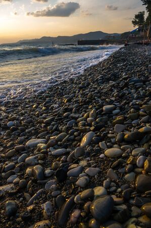rocky sea shore with pebble beach, transparent waves with foam, on a warm summer dayの写真素材