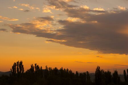 Landscape with dramatic light - beautiful golden sunset with saturated sky and clouds, peaceful nature serene background.の写真素材