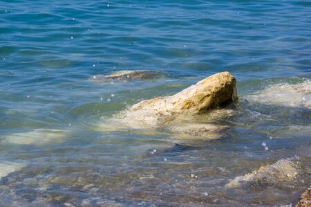 rocky sea shore with pebble beach, transparent waves with foam, on a warm summer dayの写真素材