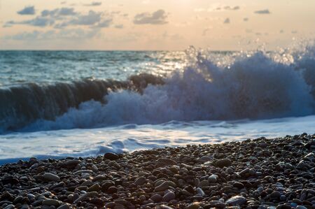 sea landscape is a pebbly beach with waves in white foam, a beautiful sky with clouds, a warm summer dayの写真素材