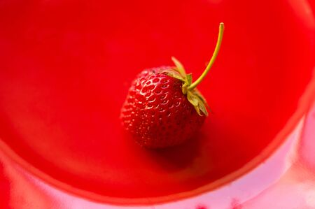 fresh ripe berries strawberries on red ceramic plate, macroの写真素材