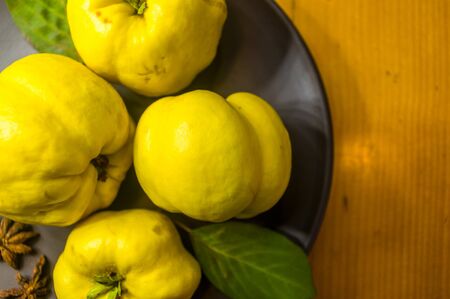 still life - large yellow quince fruits on a ceramic plate, with anise, cinnamon, and walnutsの写真素材
