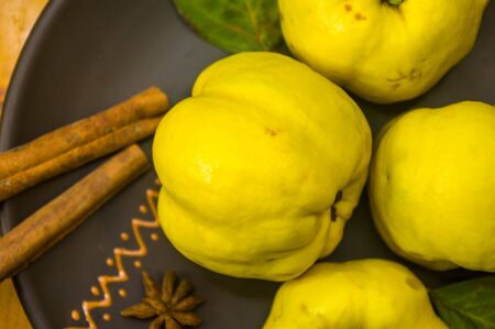 still life - large yellow quince fruits on a ceramic plate, with anise, cinnamon, and walnutsの写真素材