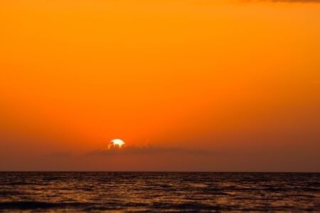 Summer sea sunset on the pebble beach, the sun, waves and clouds, beautiful dramatic lightingの写真素材