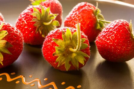 fresh ripe berries strawberries on black ceramic plateの写真素材