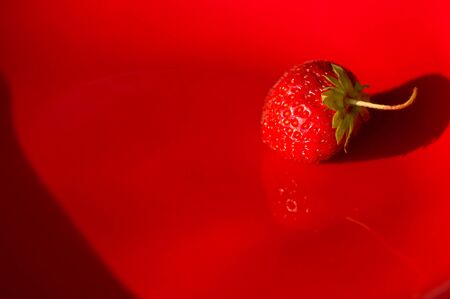 fresh ripe berries strawberries on red ceramic plate, macroの写真素材