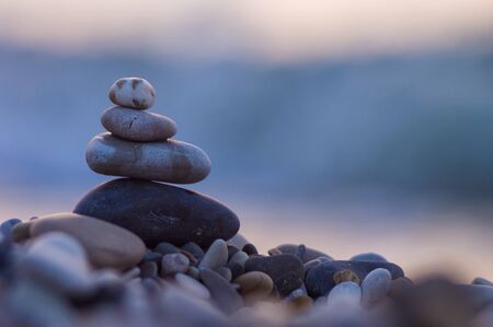 folded pyramid Zen pebble stones on the sea beach at sunsetの写真素材