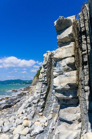 rocky sea shore with pebble beach, transparent waves with foam, on a warm summer dayの写真素材