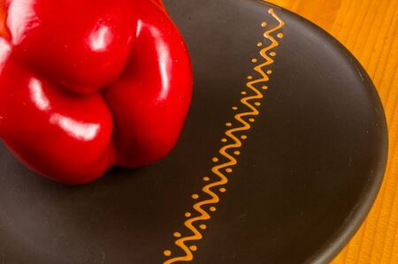 a freshest red paprika, bell pepper in ceramic plate on wooden background, close upの写真素材