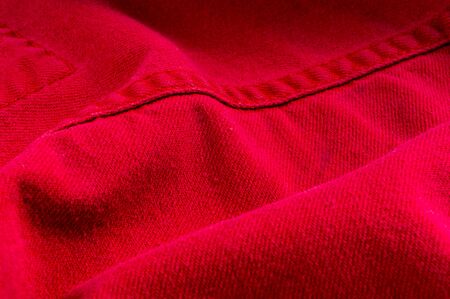 clothing items washed red cotton fabric texture with seams, clasps, buttons and rivets, macro, close-upの写真素材