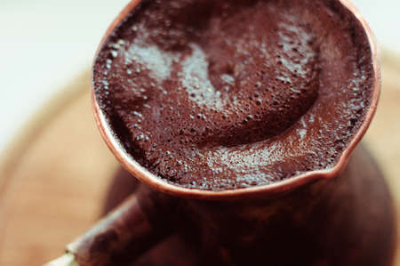 Natural coffee with thick foam, brewed in a copper cezve in the classical way, on a wooden background.の写真素材