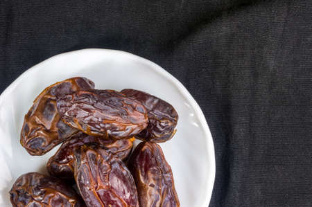 Big luxury dried date fruit in bowls on the dark surface, kurma ramadan kareem concept.の写真素材