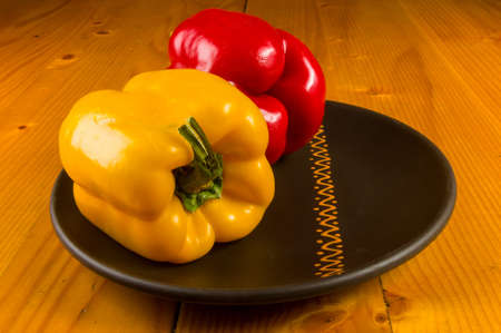 a colorful mix of the freshest red and yellow paprika, bell pepper in ceramic plate on wooden background, close upの写真素材