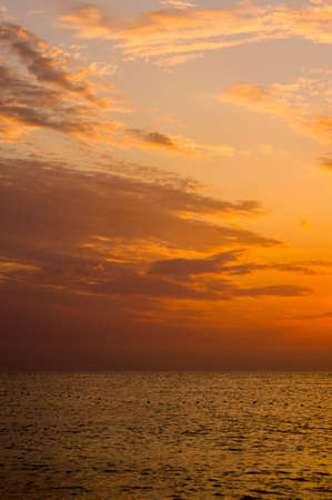 Summer sea sunset on the pebble beach, the sun, waves and clouds, beautiful dramatic lightingの写真素材