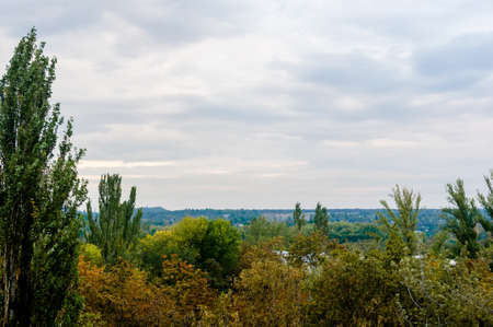 Autumn cityscape on a Sunny day - yellow and colorful autumn trees, the sky with clouds with autumn hazeの写真素材