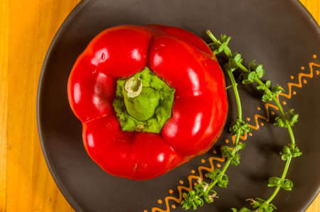 a freshest red paprika, bell pepper in ceramic plate with basil flowers on wooden background, close upの写真素材
