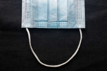 Background concept for news about the novel coronavirus COVID-19 pandemic, antiviral medical mask for protection against coronavirus. Surgical protective mask. Medical respiratory bandage face and thermometer, lettering on copy space.の写真素材