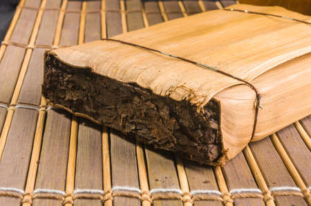 Chinese pressed PU-erh tea in bamboo leaf packaging on a bamboo Mat, close-upの写真素材