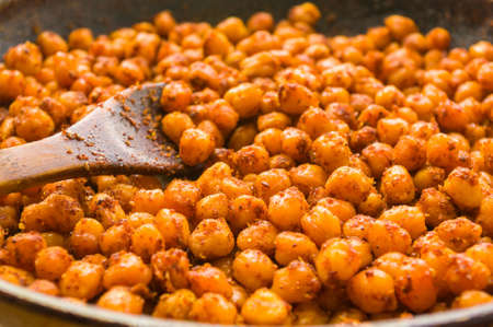 Cooking chickpeas with spices in a pan, close upの写真素材