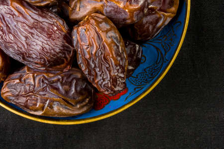 Big luxury dried date fruit in bowls on the dark surface, kurma ramadan kareem concept.の写真素材