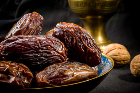 Big luxury dried date fruit in bowls on the dark surface, kurma ramadan kareem concept.の写真素材