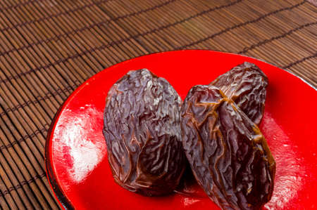 Big luxury dried date fruit in bowls on the bamboo mat, kurma ramadan kareem concept.