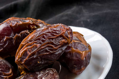 Big luxury dried date fruit in bowls on the dark surface, kurma ramadan kareem concept.の写真素材