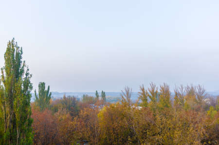 Autumn cityscape on a Sunny day - yellow and colorful autumn trees, the sky with clouds with autumn hazeの写真素材