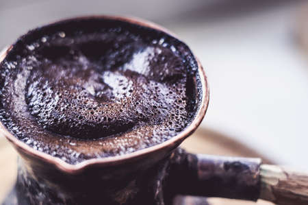Natural coffee with thick foam, brewed in a copper cezve in the classical way, on a wooden background.の写真素材